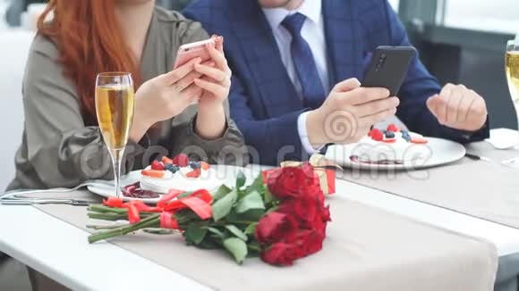 在餐馆里情侣们使用智能手机进行浪漫约会视频的预览图