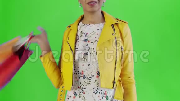 美国黑人妇女的肖像与购物袋和金钱风扇在绿色背景在工作室黄色夹克视频的预览图