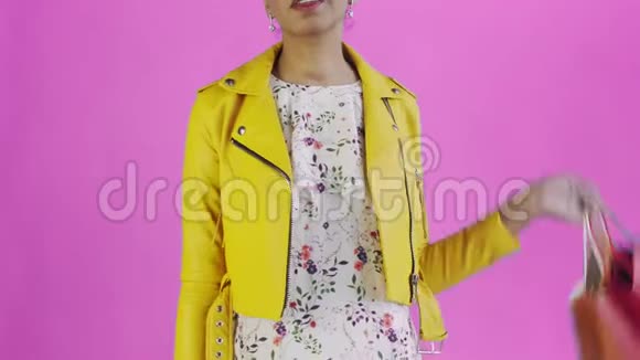 美国黑人妇女的肖像带购物袋和GOLD信用卡在粉红色背景在工作室黄色夹克视频的预览图