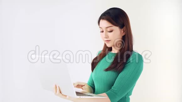 漂亮的亚洲女人在笔记本电脑上打字灰色背景视频的预览图