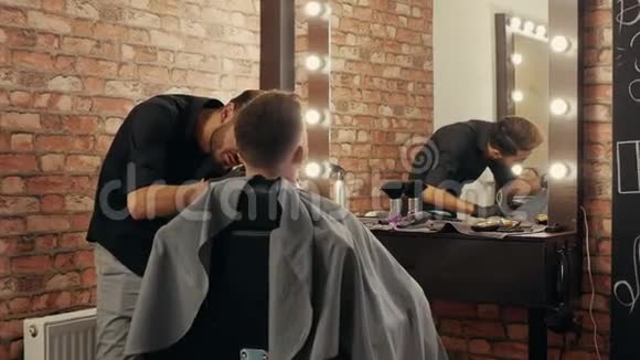 理发师给留胡子的男人刮胡子在男性沙龙里用电动剃须刀穿着剃须刀修胡须的人视频的预览图