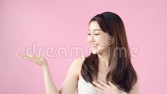 随意的女人在粉红色的背景上呈现复制空间美女画像在工作室用手势宣传产品视频的预览图