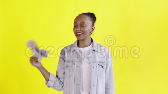 满意的非洲裔美国妇女的钱显示拇指黄色背景让夹克视频的预览图