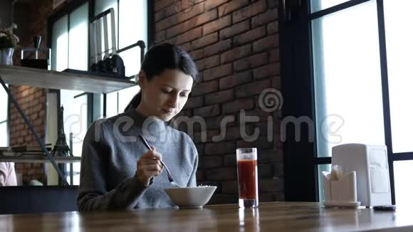 美丽的年轻快乐的女人坐在咖啡馆的桌子旁享受着这顿饭饥饿的女人吃美味的午餐视频的预览图