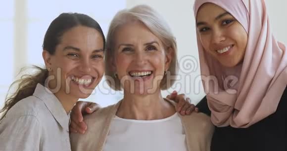 三个微笑的女性朋友拥抱看镜头视频的预览图