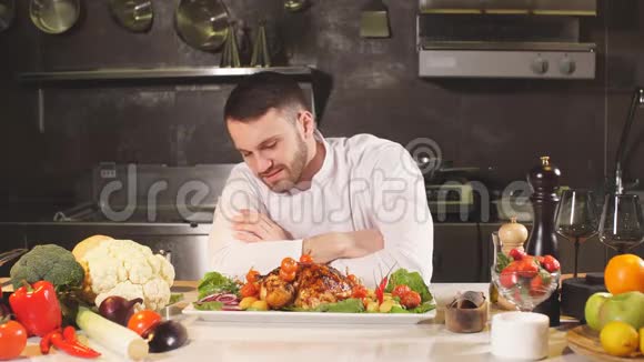年轻的男厨师呈现他的特殊菜肴他站在一个大餐厅厨房里视频的预览图