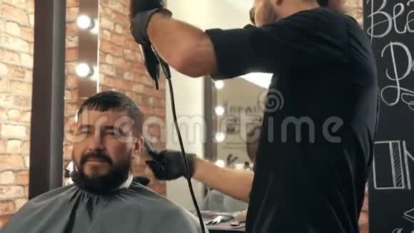 理发师在男性美容院烘干男性头发在理发店里用吹风机关闭理发师吹胡子的男士头发视频的预览图