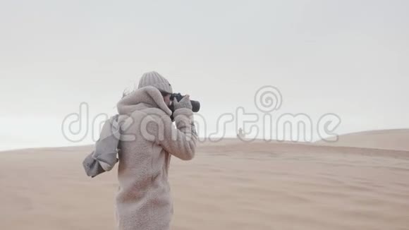 快乐女记者在极端风慢运动下拍摄沙丘海滩灯塔的大气景象视频的预览图