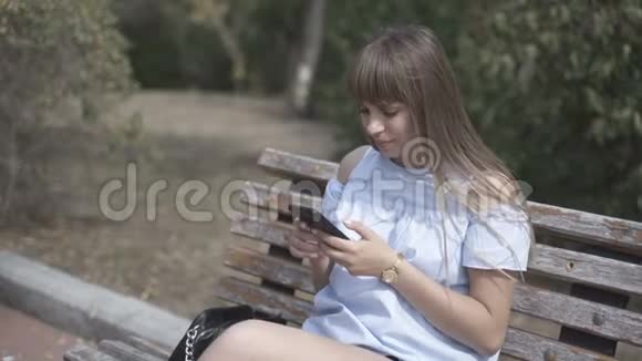 坐在长凳上拿电话的女孩视频的预览图