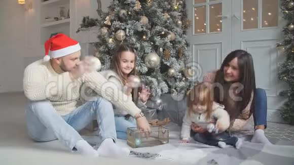 父母和两个小孩在室内圣诞树附近玩得很开心视频的预览图