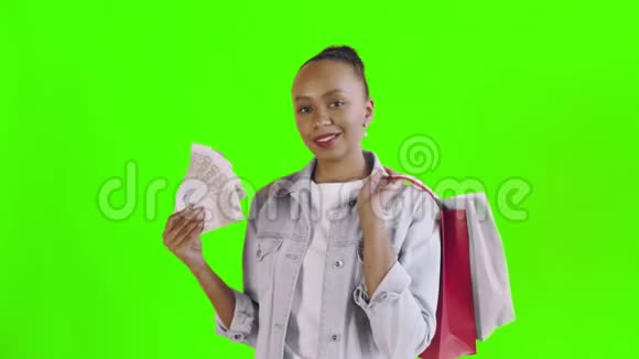 美国黑人妇女的肖像与购物袋和金钱风扇在绿色背景在工作室琼夹夹克视频的预览图