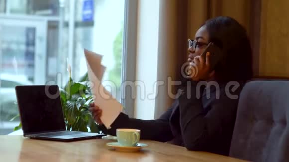 非裔美国女商人手提电脑和纸女孩和生意伙伴通电话视频的预览图