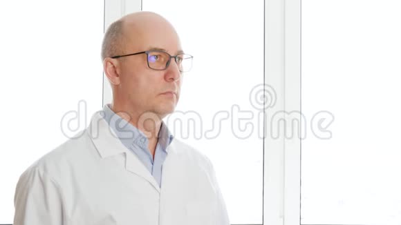 肖像科学家戴着眼镜和白大褂的秃头男子看着白色的窗户背景白人生物工程师视频的预览图