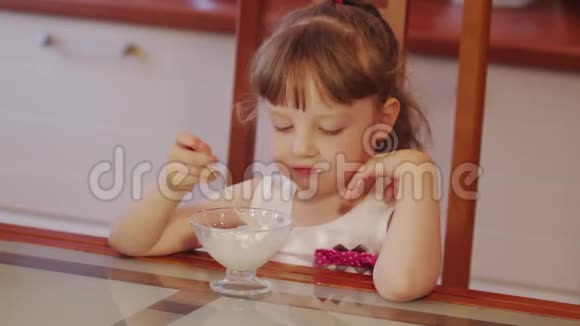 可爱的小女孩笑着在厨房的碗里吃冰淇淋近距离射击视频的预览图