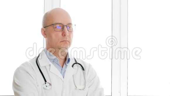 肖像医生穿着白色医用长袍带电话和内窥镜点头男性医务工作者用听诊器视频的预览图