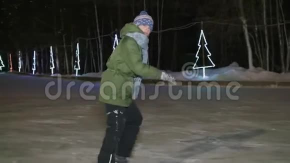 在冬季公园的夜间冰场上少年男孩在溜冰鞋上滑冰快乐的男孩骑着冰鞋在冬天的溜冰场视频的预览图