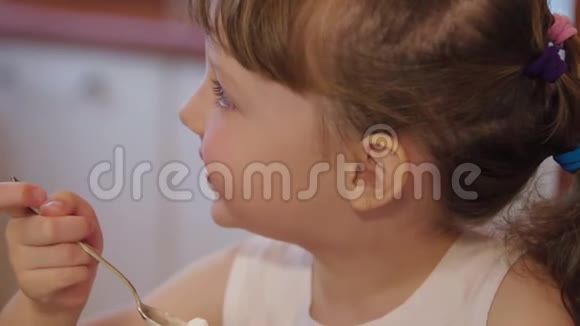 小女孩在厨房里在家聊天吃冰淇淋可爱的小女孩笑着吃冰淇淋视频的预览图