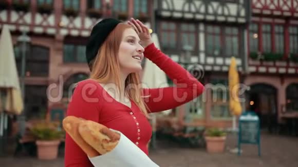 穿着黑色贝雷帽的法国女孩手里拿着纸包的面包微笑视频的预览图