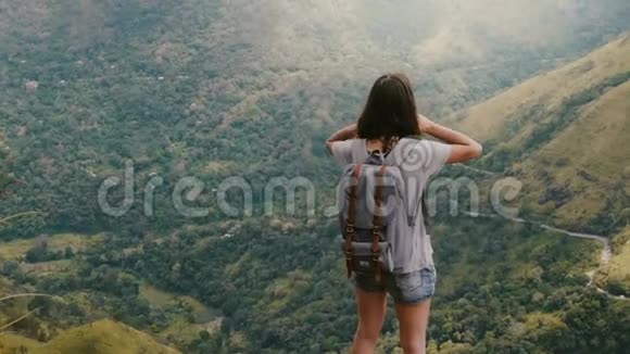 后景幸福年轻的旅游女性背包和手臂张开触摸头发观看史诗般的斯里兰卡山脉视频的预览图