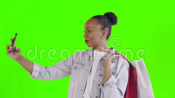 美国黑人妇女带着购物袋的肖像正在工作室的绿色背景上自拍琼夹夹克视频的预览图