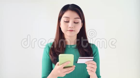 幸福的微笑年轻女孩拿着信用卡通过智能手机在网上购物与白人隔绝视频的预览图