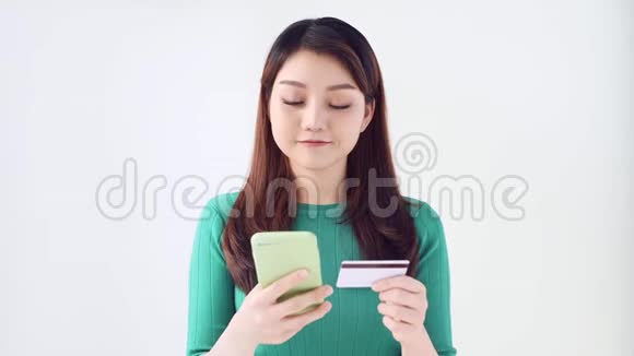 幸福的年轻女性在网上购物和用信用卡和智能手机购物的肖像与光线隔绝视频的预览图