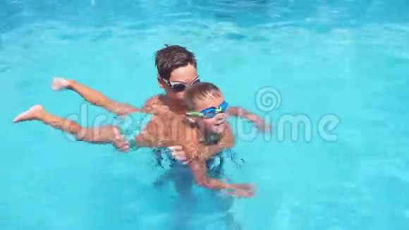 孩子教他的小男孩哥哥在游泳池里游泳男孩移动手臂和腿笑视频的预览图