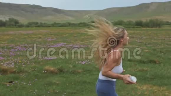 镜头跟随时髦的年轻女人穿着白色的t恤短牛仔裤飘扬的长发一个女孩在便携式电脑前跳舞视频的预览图