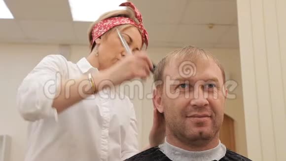 理发师给人理发站在他身后对着镜头和镜子那个女孩的蝴蝶结是红色的视频的预览图