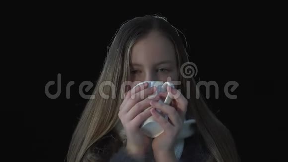 可爱的女孩想取暖喝热饮拿着杯子在黑色的背上微笑着可爱视频的预览图