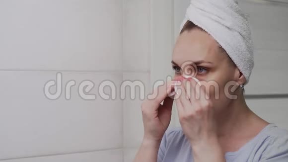 成年女性头上有一条毛巾涂抹乳液照镜子享受自然的美丽和健康视频的预览图
