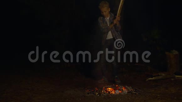 十几岁的男孩用木棍在营地里用火花敲打着滚烫的煤希克族男孩在冷却的过程中视频的预览图