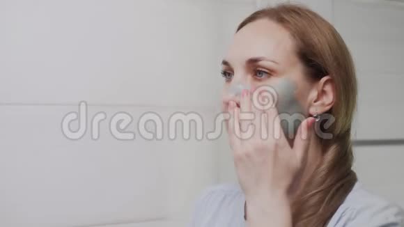 特写成年女性脸上涂着黏土面具照镜子视频的预览图