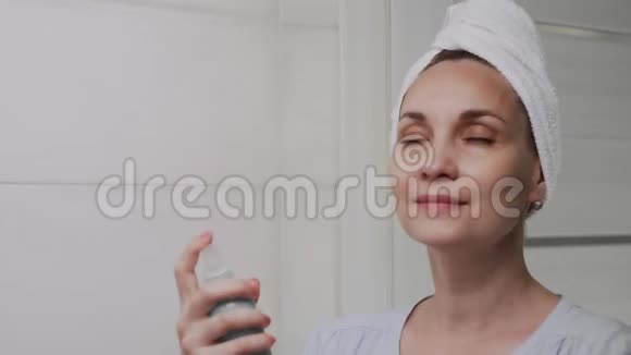 成人女性头上有毛巾用水喷雾补充皮肤水分视频的预览图