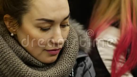 穿着冬装的漂亮女士坐地铁看手机屏幕视频的预览图