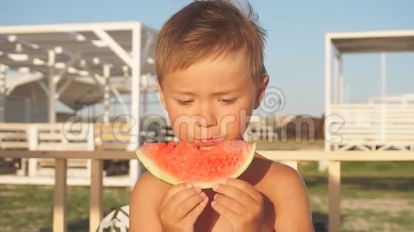 可爱的孩子坐在沙滩椅上吃切片西瓜夏日特写视频的预览图