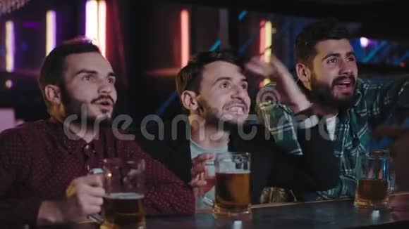 在一个酒吧里一群很有吸引力的人在镜头前聚在一起看一场电视比赛视频的预览图