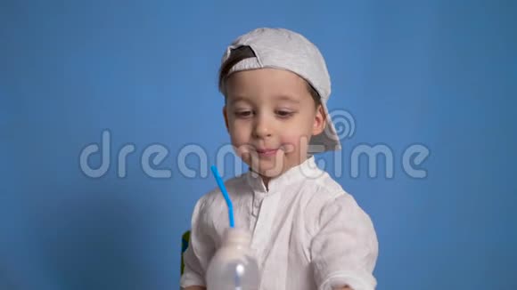 穿着白色衬衫和帽子的孩子从一瓶酒中喝啤酒视频的预览图