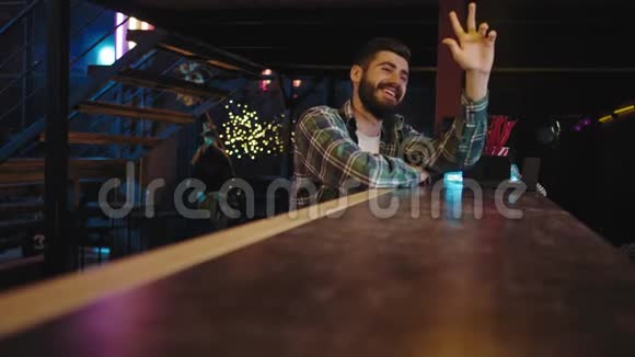 年轻男子魅力十足笑容满面坐在酒吧桌旁等着喝酒他端起酒杯视频的预览图