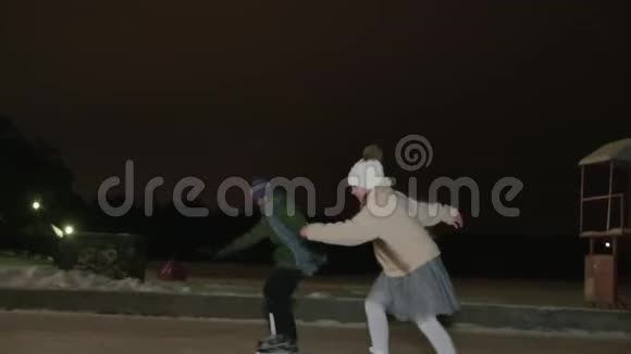 快乐的男孩和女孩青少年在冬季黑暗公园的溜冰场上滑冰微笑的姐姐和哥哥在滑冰视频的预览图