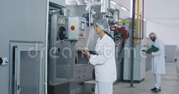 在大面包厂工作一天两个工人一个女人一个男人检查工业机器一个老面包师一个走来走去视频的预览图