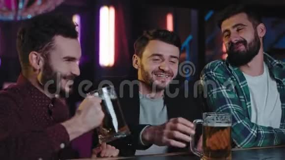 在酒吧里三个男人在酒吧里微笑着喝着大玻璃杯中的啤酒他们享受着气氛和气氛视频的预览图