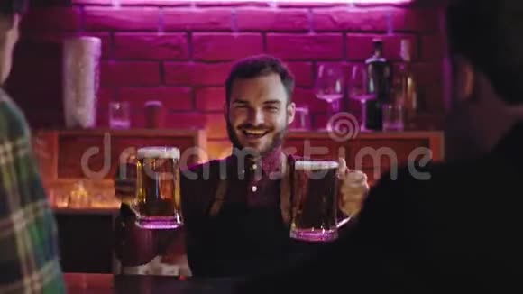 在一家现代化的酒吧里快乐而英俊的酒保把一大杯啤酒送给他的酒吧桌上的酒保视频的预览图