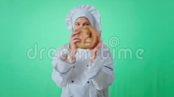 Chroma关键工作室吸引人的面包师女士穿着制服一边在前面玩一个新鲜的椒盐卷饼一边跳舞视频的预览图