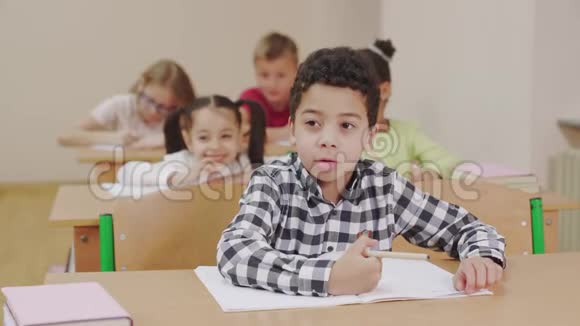 男孩在教室里用抄本写作视频的预览图