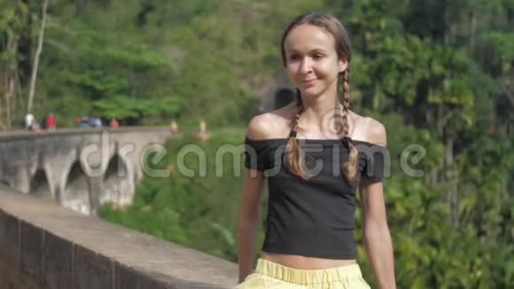 女孩坐在桥栏上享受着狂野的热带自然视频的预览图