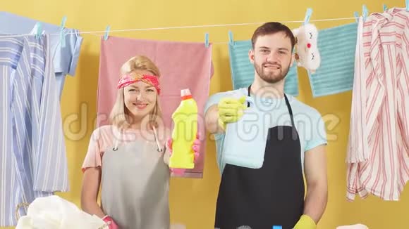 快乐的一对夫妇拿着装有清洁剂的瓶子洗衣服视频的预览图
