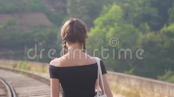 穿着黑色上衣的女孩在大自然的特写中走向铁路视频的预览图