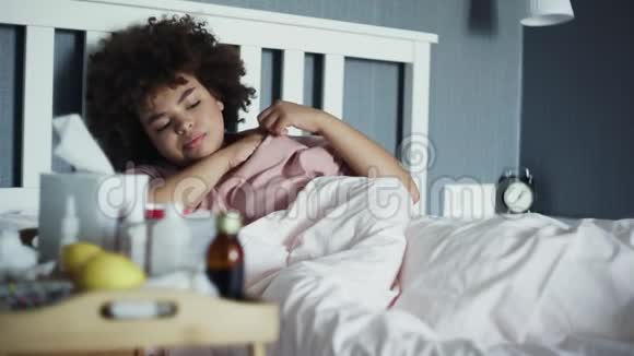 生病的非裔美国女孩患流感躺在家里的床上我年轻的黑人女人在寒冷的温度下视频的预览图