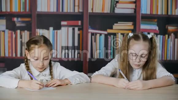 女生在书架背景上看同学笔记本在校考古怪的女生偷看回答视频的预览图